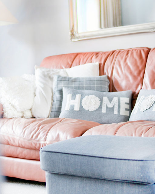 Фотография дивана с мягкими подушками, на одной из которых написано Home.