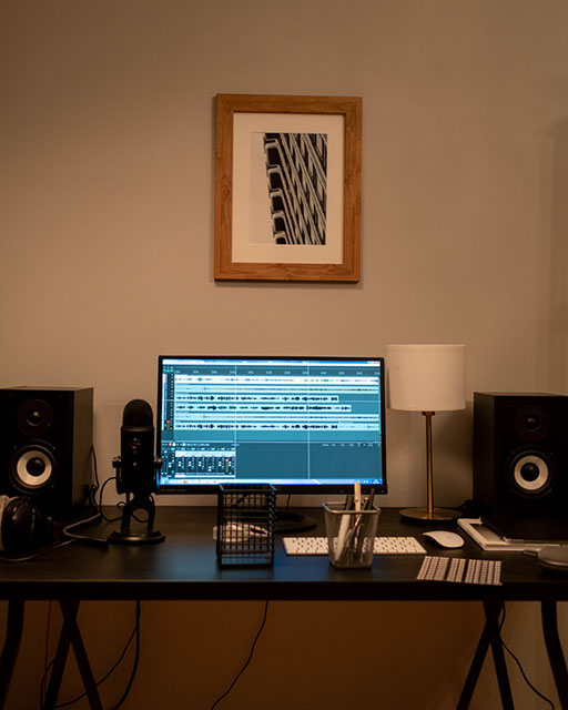 Фотография рабочего стола с компьютером, микрофоном и колонками.